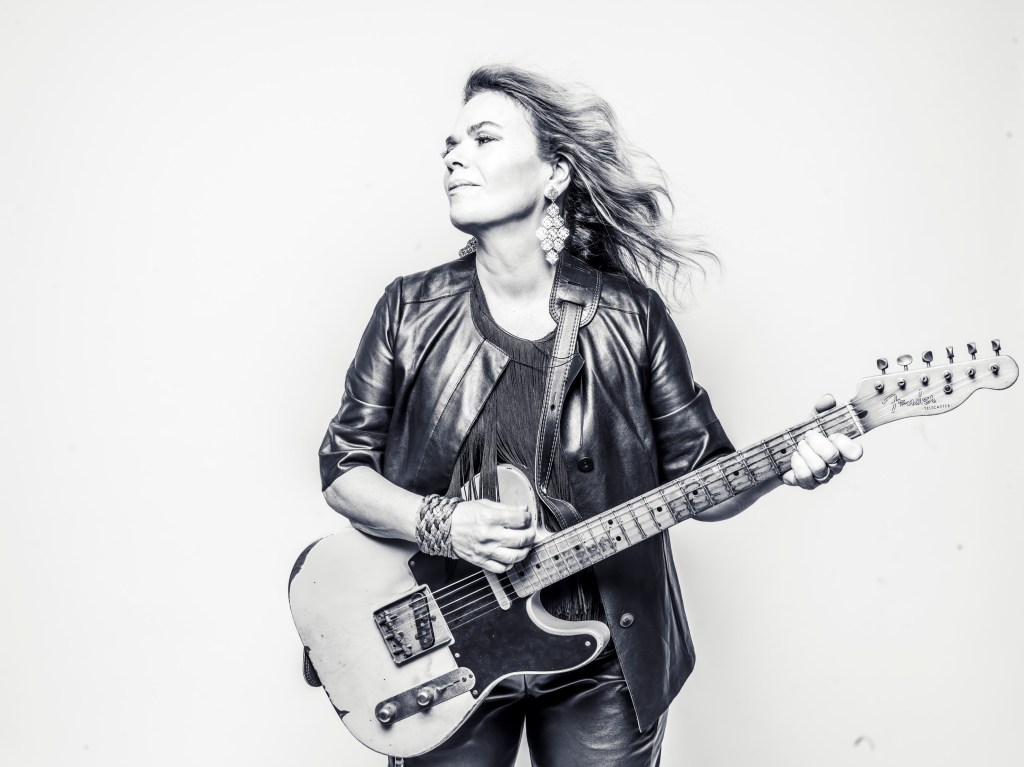 Australian singer-songwriter Paula Punch, wearing a leather jacket and playing a vintage Fender electric guitar.